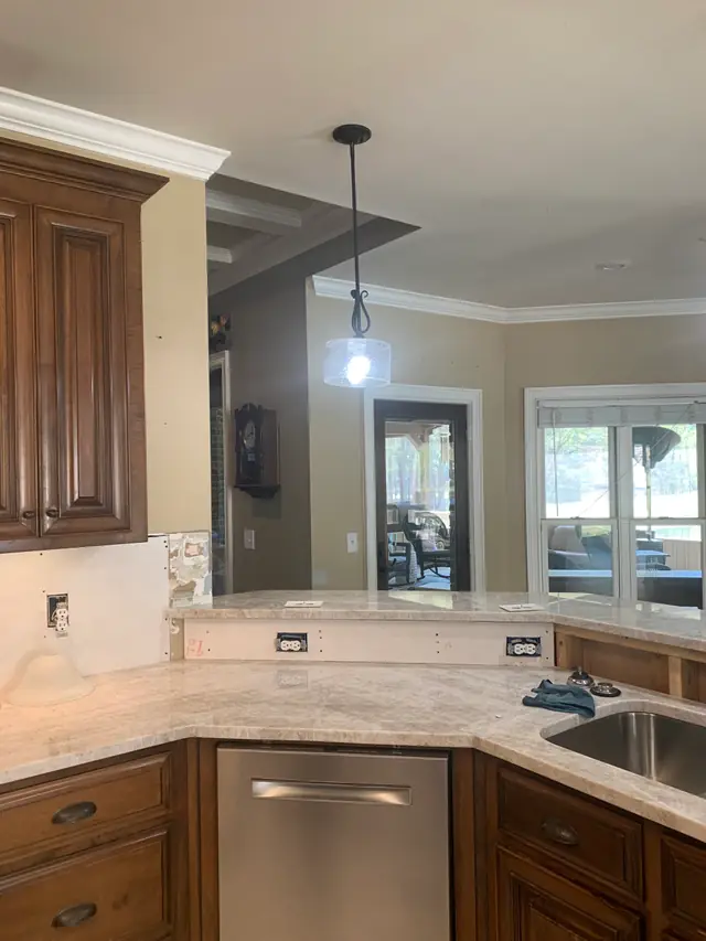Kitchen with pale quartzite countertops set, backsplash removed, and red marker notes on the exposed wall board